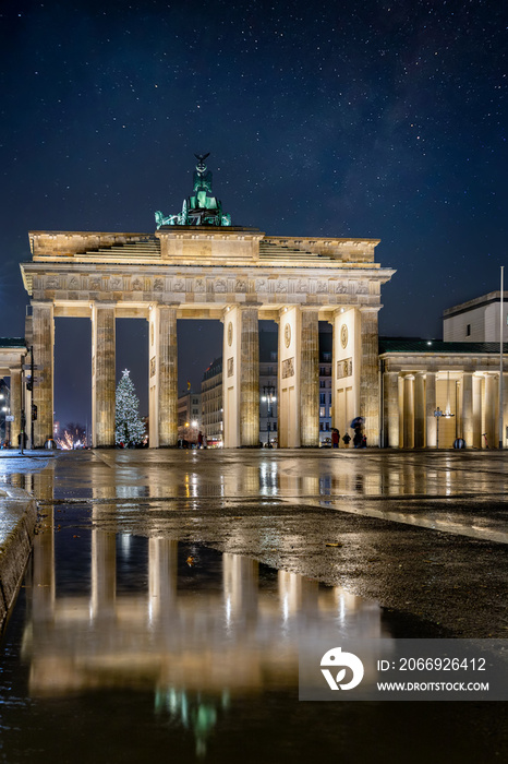 Night view to the famous Brandenburger Tor in Berlin, Germany, during winter time with reflections in the rain puddles