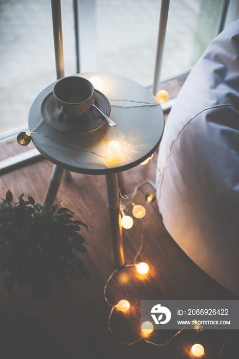 Cup of coffee and warm Christmas lights on a table