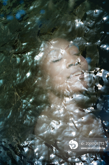 Double exposure, close-up of an attractive dark skinned girl combined with ripples of lake water