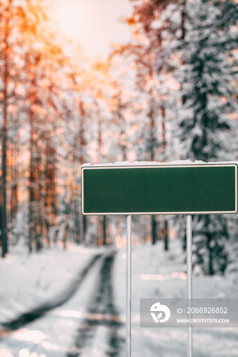 Blank green road sign in winter. Design template for information posts near a highway in winter.