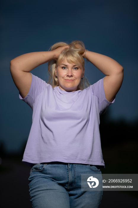 Plump middle aged woman posing in jeans on the street, overweight xxl. A full girl enjoys life.