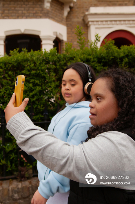 Two curvy women with Down Syndrome taking selfies in with their coffees