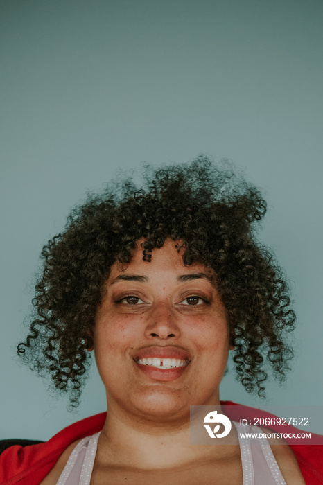 closeup portrait of a plus size afro indigenous person smiling on blue background