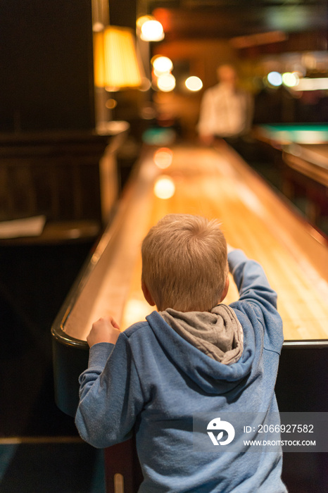 Young kid in blue hoodie playing shuffleboard