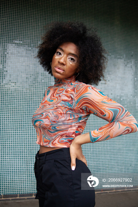 Young curvy woman with vitiligo posing in front of fun tiled wall