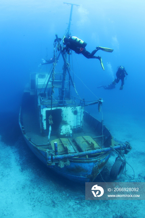 Scuba Divers Exploring underwater ship wreck