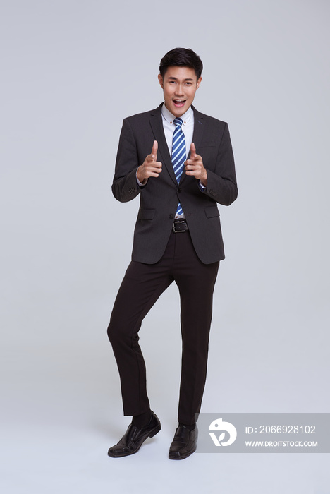 portrait of young Asian businessman smiling and pointing hand front of while standing isolated on studio white background.