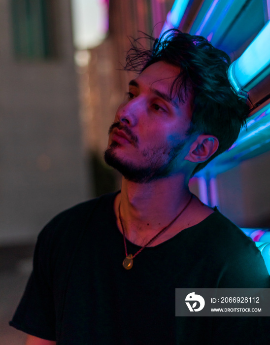 a young handsome man leaning on the neon display at night