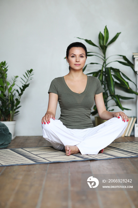 Young happy healthy fitness beautiful woman female doing and workout on yoga mat opposite at modern bedroom at home.