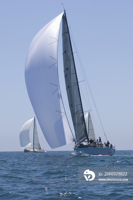 Overview of sailboats racing in the blue and calm ocean against sky