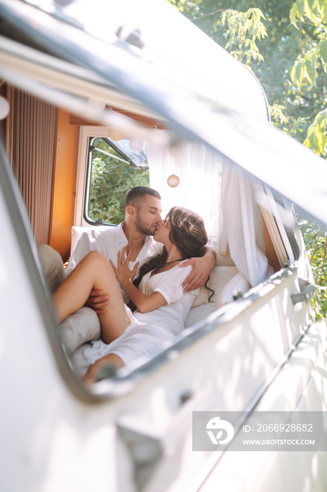 Happy newlyweds elaxing in rv, camping in a trailer. Couple embracing each other and smiling. Romantic moment. Together. Wedding. Marriage.