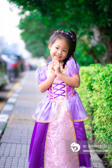 Portrait of cute smiling little girl in princess costume standing in the park