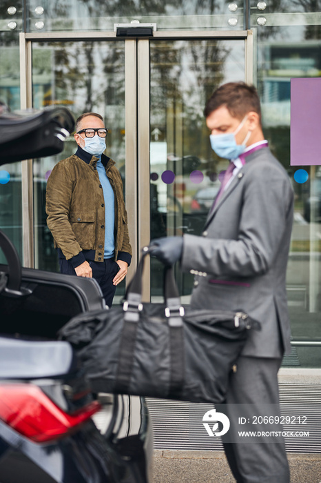 Chauffeur holding his client baggage with one hand