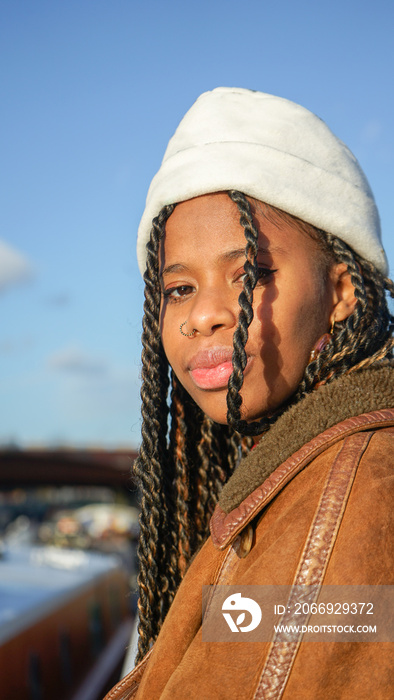 Portrait of young woman with braided hair and cap outdoors