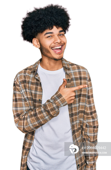 Young african american man with afro hair wearing casual clothes cheerful with a smile of face pointing with hand and finger up to the side with happy and natural expression on face