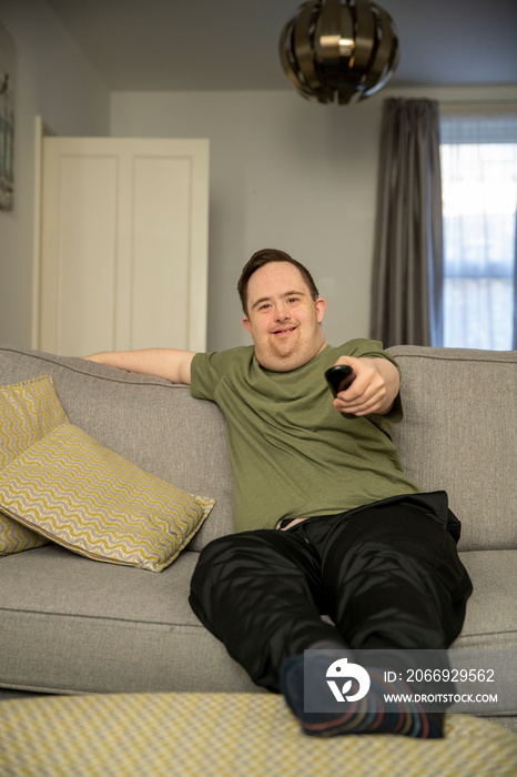 Man sitting on sofa and using remote control