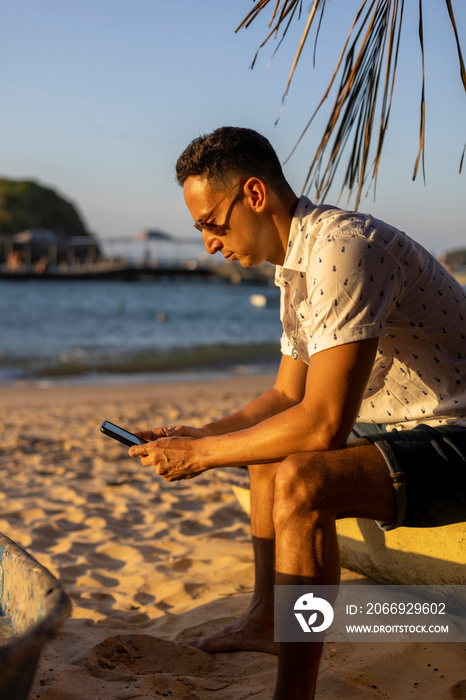 Man sitting at beach and using smart phone