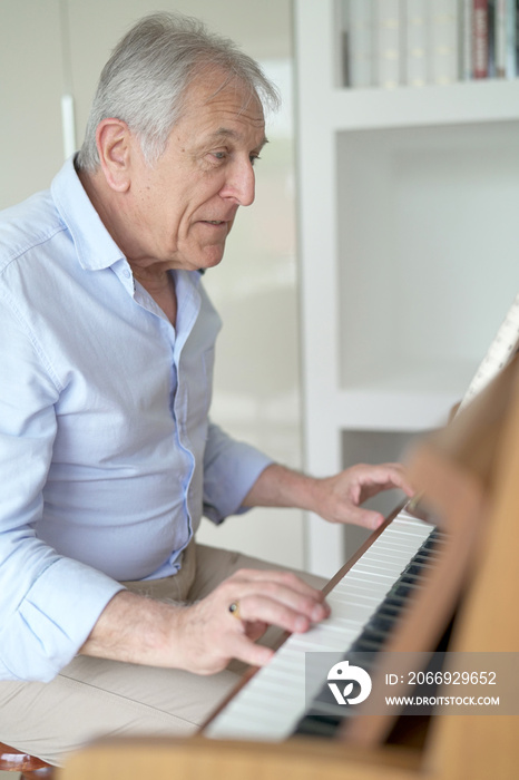 Senior man playing the piano at home