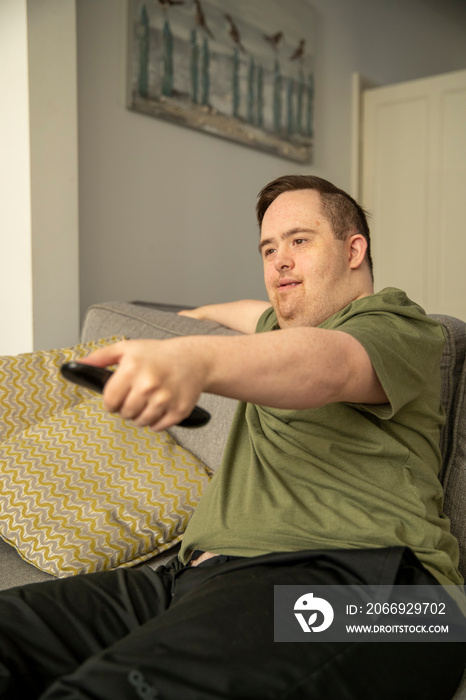 Man sitting on sofa and using remote control