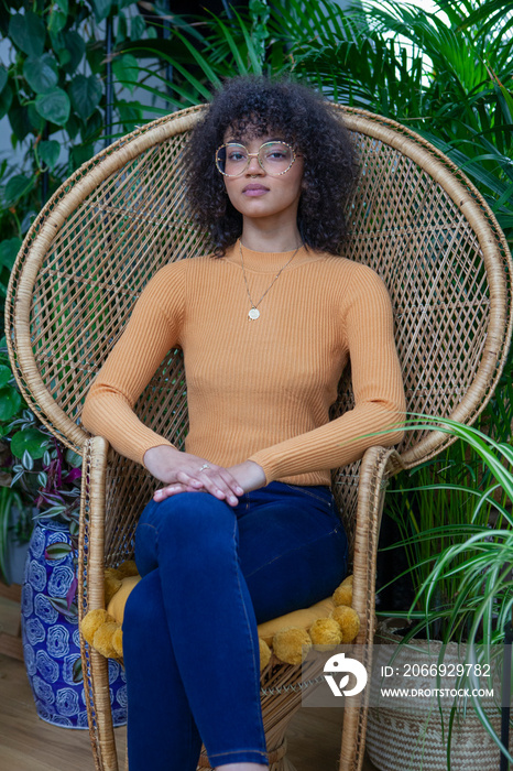 Portrait of woman sitting in tropical style rattan armchair