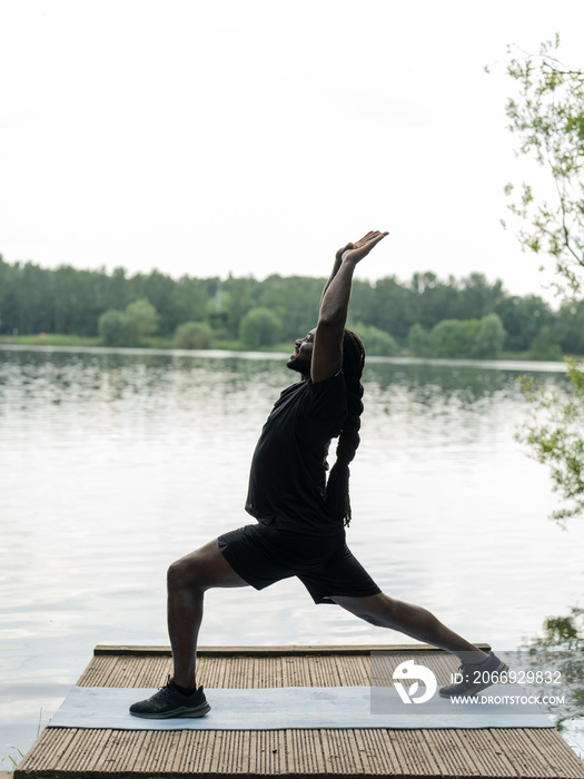 Man practicing yoga by lake