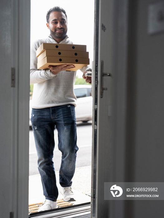 Smiling man bringing pizza home