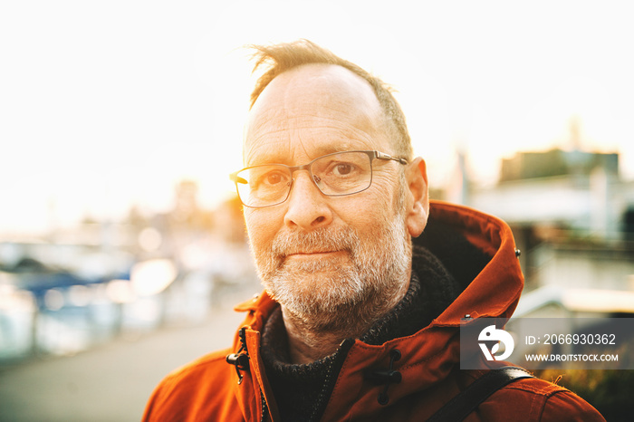 Outdoor portrait of middle age man wearing eyeglasses and orange winter jacket