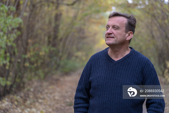 People and lifestyle concept. Happy middle-aged unshaven man outdoors on nature background in autumn. Adult man portrait closeup