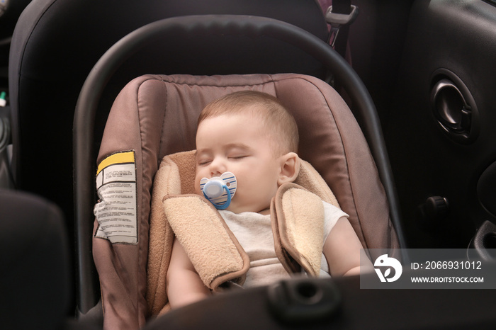 Adorable baby sleeping in child safety seat inside of car