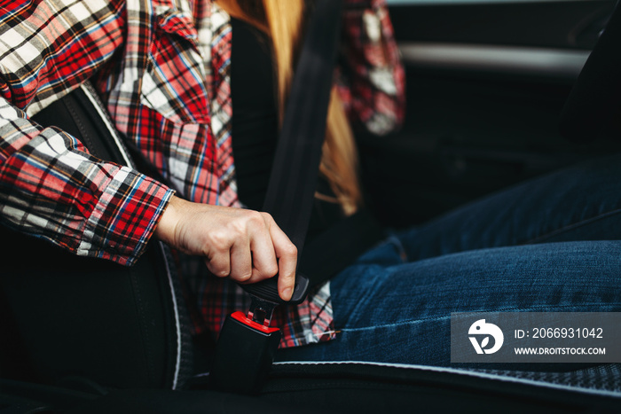 Woman driver fastens her seat belt in the car