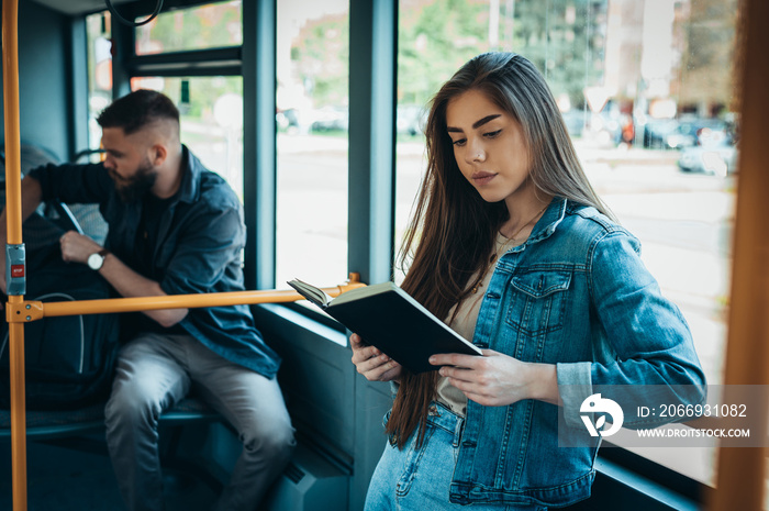 Young beautiful woman reading a book in a bus