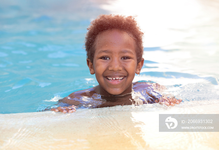 Little african child splashing out in the pool