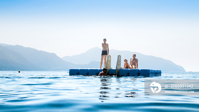 Family swimming and relaxing on floating pontoon at sea