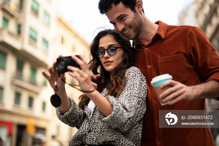 Traveling couple taking photos with camera. Loving couple walking through the city..