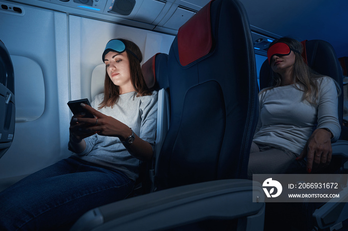 Female passenger typing on smartphone during night flight
