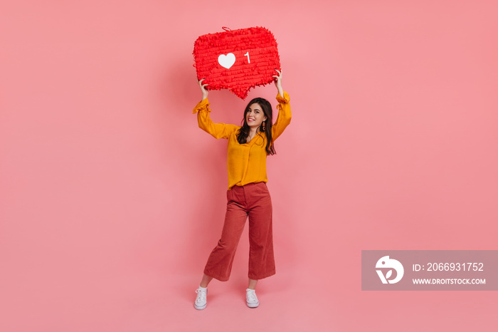 Full-length portrait of cheerful girl in culottes and yellow blouse holding like instagram sign