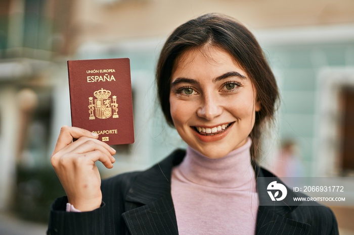 Young beautiful businesswoman smiling happy holding spainish passport at the city.