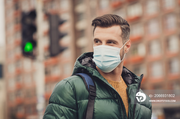 Photo of handsome positive good mood young man wear green windbreaker schoolbag face respirator walking outside city street