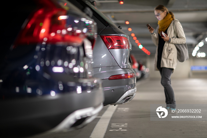 Underground garage or modern car parking with lots of vehicles, perspective of the row of the cars with a female driver looking for her vehicle