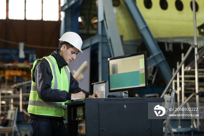 Portrait of a man , factory engineer in work clothes controlling the work process at the airplane manufacturer.