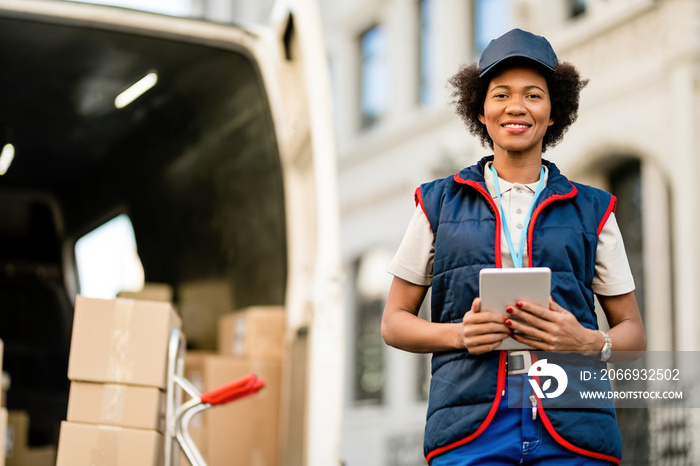 Portrait of happy African American delivery woman with a touchpad outdoors.