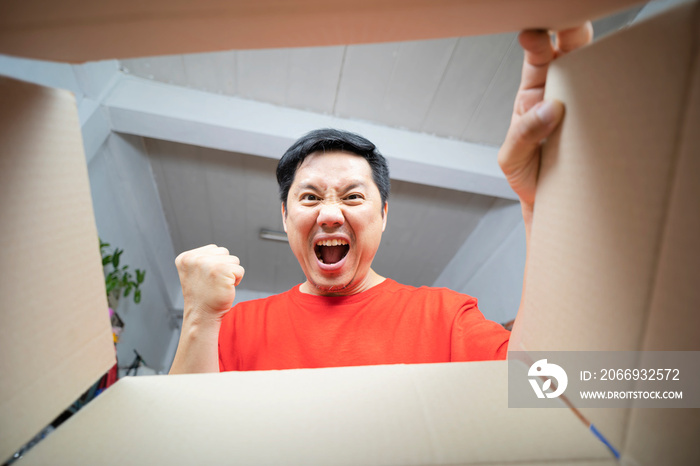 Man sitting on couch in living room and opening carton box