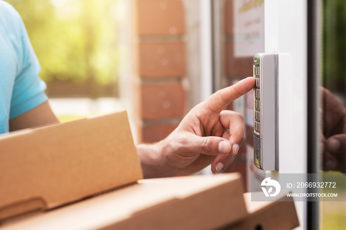 Delivery man with a packages is pressing buttons on a doorbell