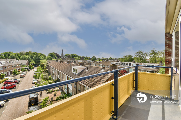 an apartment balcony with yellow railings and blue sky in the photo is taken from outside, looking out onto the street