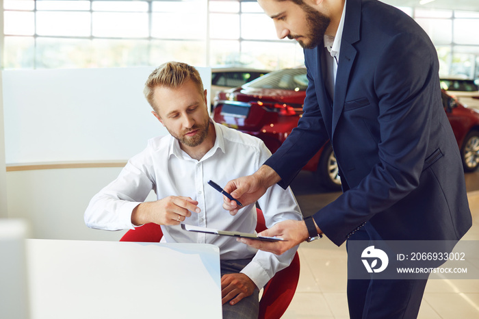 A man buys a car in a car showroom.