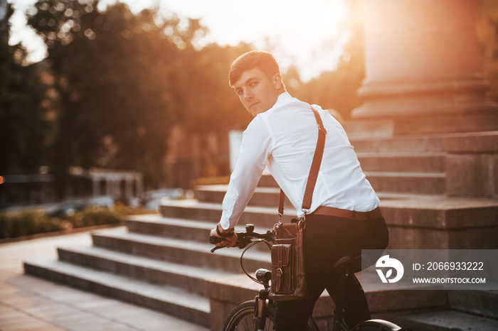 Politician goes home from his job. Businessman in formal clothes with black bicycle is in the city