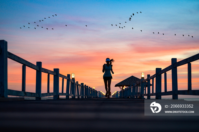 silhouette of  healthy woman jogging alone at daily morning on the wooden jetty bridge or pier, daily exercise workout running at light of sunset