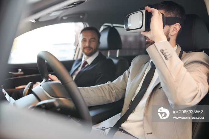 Side view portrait of handsome bearded  businessman wearing VR headset sitting behind wheel of luxury car