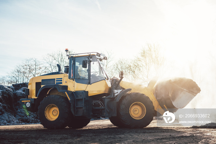 Wheel loader working on heap with biomass for composting