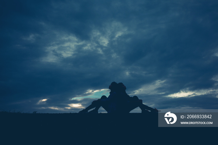 Silhouette of two women sitting lean